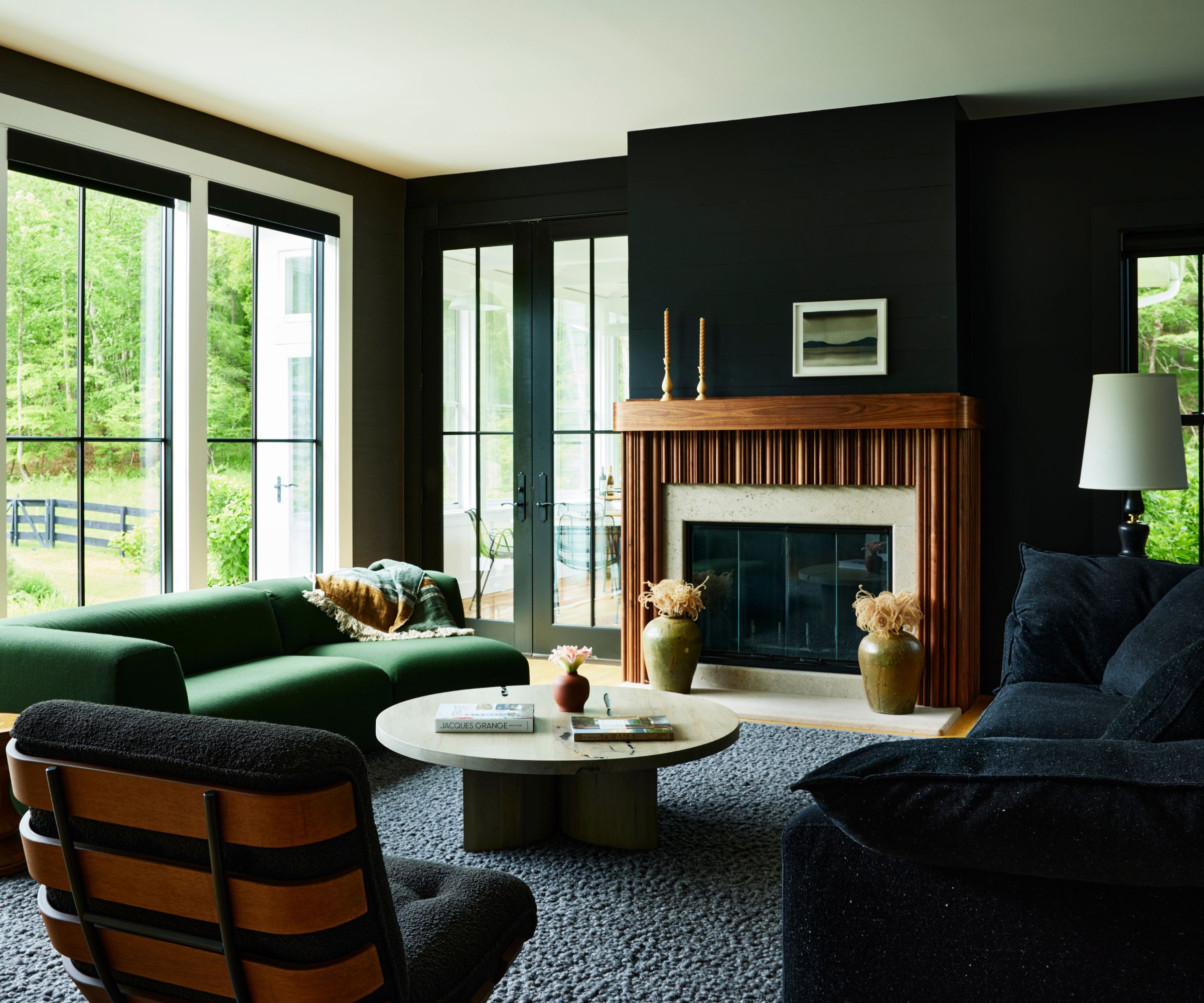 modern living room with black walls and sofa, a gray rug, and a green sofa in front of sliding glass doors