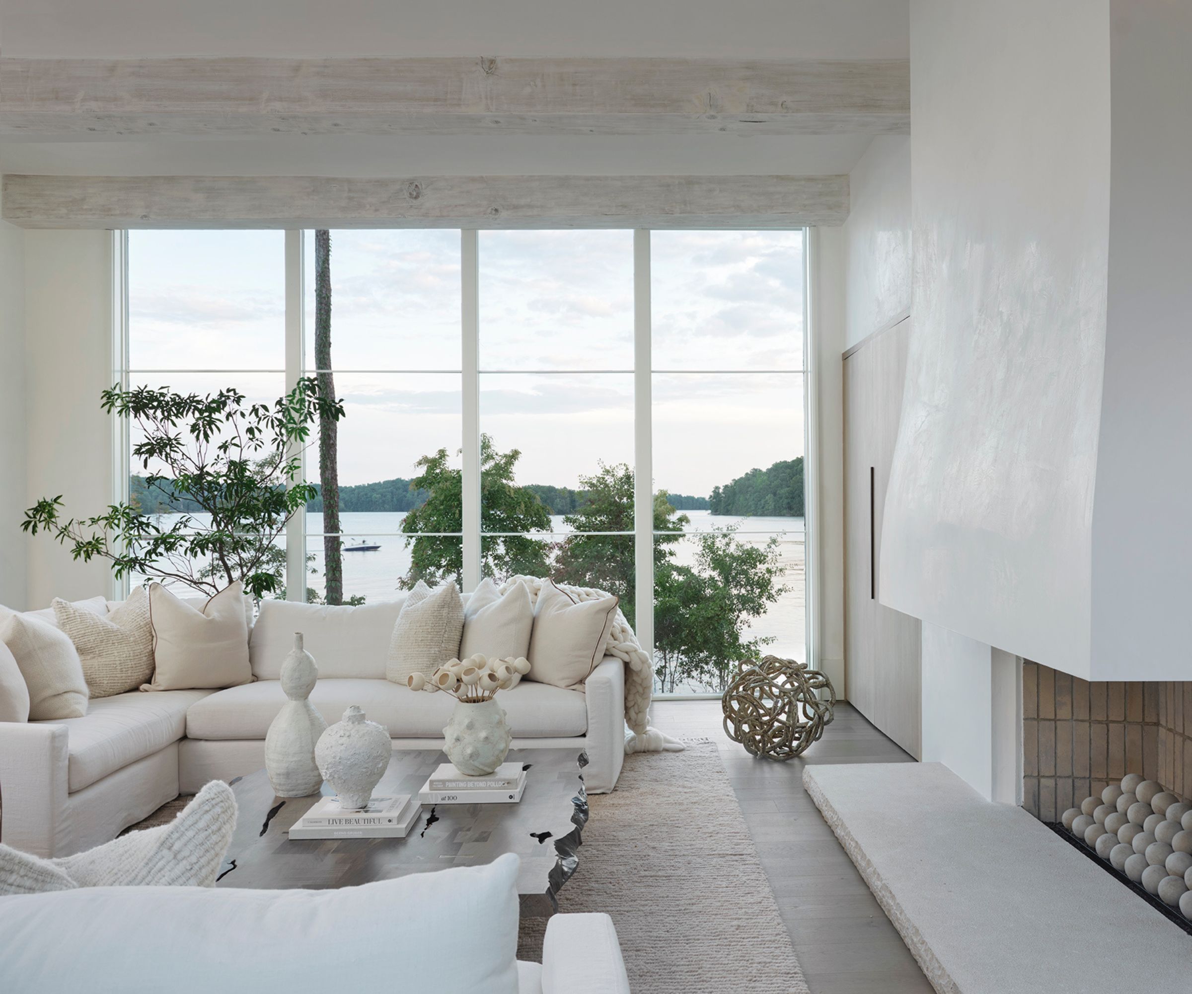 modern living room with all-white color scheme, large floor-to-ceiling windows with a view of the lake