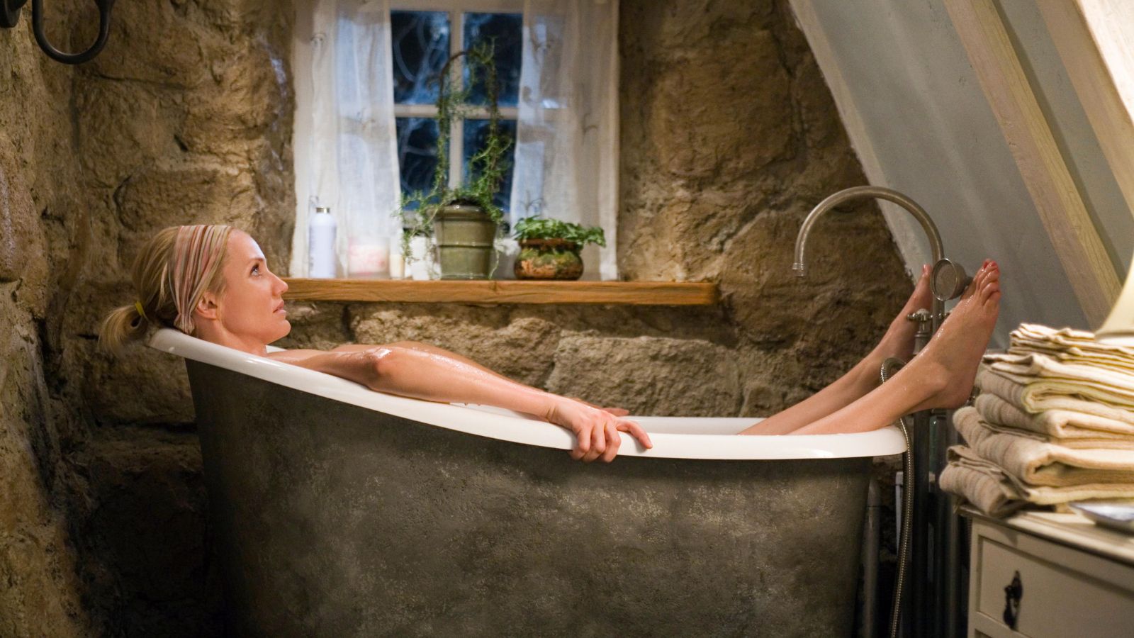 still image from Nancy Meyer&#039;s movie &#039;The Holiday&#039; of actress Cameron Diaz in a tiny claw foot bathtub in a bathroom with stone walls and a sloped ceiling