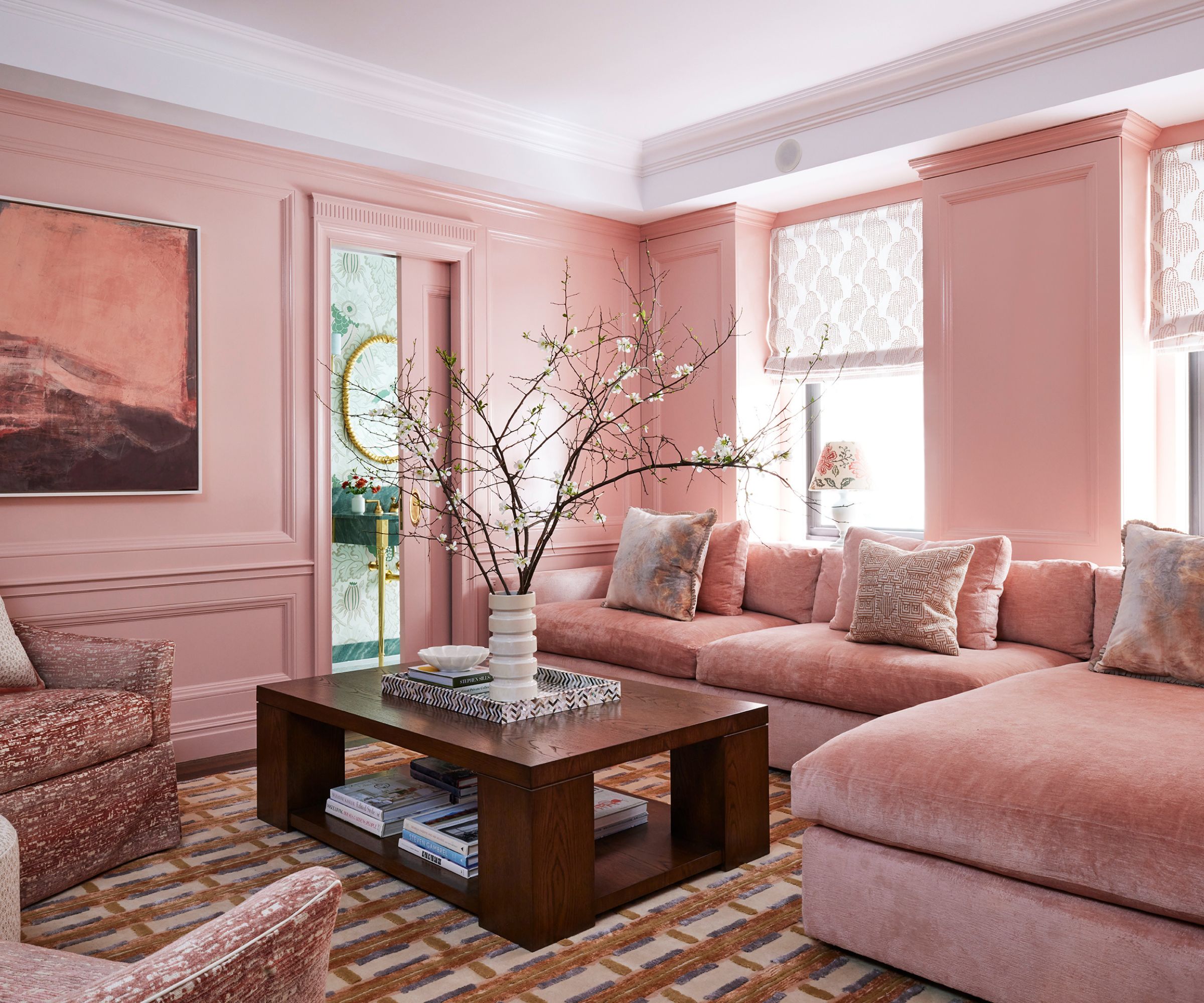living room color-drenched pink with pink corner sofa, wooden coffee table, and patterned rug